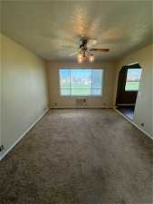 Empty room with ceiling fan, a healthy amount of sunlight, and carpet floors