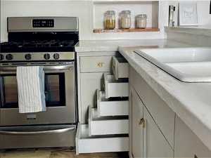 Kitchen with sink, stainless steel gas range, and light wood-type flooring