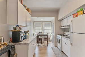 Unit 1006 - Kitchen featuring white appliances and white cabinetry