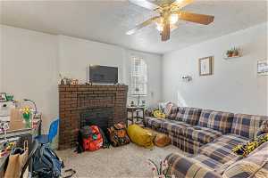Unit 1008 - Living room featuring a textured ceiling, ceiling fan, carpet floors, and a brick fireplace