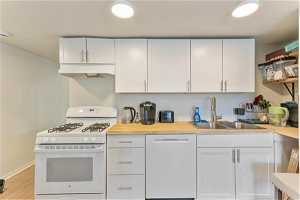 Unit 1004 - Kitchen with white cabinets, white appliances, and custom exhaust hood