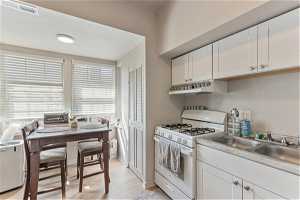 Unit 1006 - Kitchen featuring white cabinets, white gas range oven, and light wood-type flooring