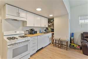 Unit 1004 - Kitchen with light hardwood / wood-style floors, white appliances, white cabinets, and sink