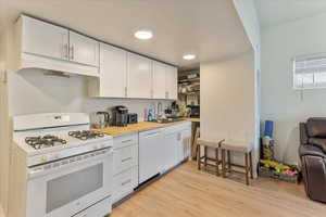 Unit 1004 - Kitchen with light hardwood / wood-style floors, white appliances, white cabinets, and sink