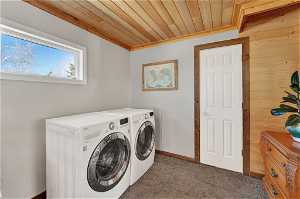 Laundry area with dark colored carpet, wooden ceiling, and washer and dryer