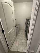 Washroom with washing machine and dryer and light tile floors