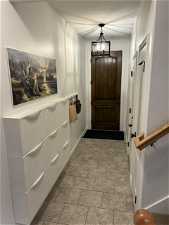 Doorway to outside featuring light tile floors and an inviting chandelier