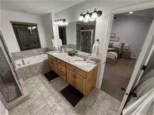 Bathroom with tile flooring, independent shower and bath, and double sink vanity
