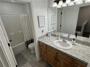 Full bathroom featuring shower / tub combo with curtain, toilet, tile floors, and vanity with extensive cabinet space