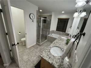 Full bathroom with dual sinks, toilet, independent shower and bath, and large vanity