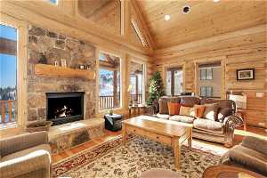 Living room featuring a wealth of natural light, a stone fireplace, light hardwood / wood-style flooring, and high vaulted ceiling