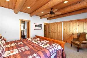 Carpeted bedroom featuring wood ceiling, beam ceiling, and ceiling fan