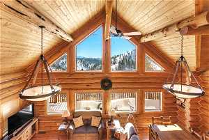 Living room with rustic walls, beam ceiling, and high vaulted ceiling