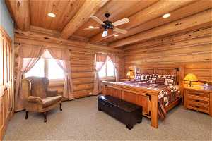 Carpeted bedroom with wood ceiling, rustic walls, beamed ceiling, and multiple windows