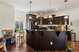 Kitchen featuring decorative light fixtures, black appliances, and dark wood-style flooring