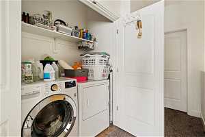 Laundry area featuring dark colored carpet and washer and dryer
