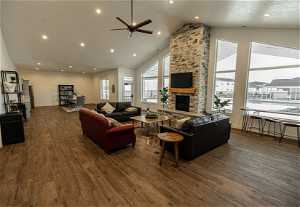 Living room featuring high vaulted ceiling, a fireplace, dark wood-type flooring, and ceiling fan