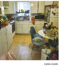 Kitchen with white fridge, sink, light tile flooring, and white cabinetry