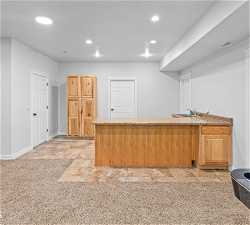 Kitchen with light carpet, sink, and light stone countertops