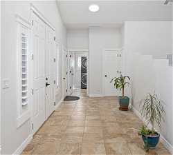 Foyer entrance featuring light tile floors and stacked washer / drying machine