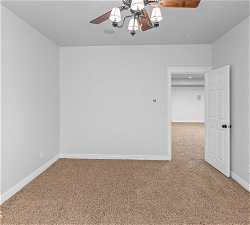 Spare room with light colored carpet and ceiling fan with notable chandelier