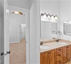 Bathroom with ceiling fan and dual vanity