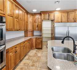 Kitchen featuring sink, light tile floors, stainless steel appliances, and light stone countertops