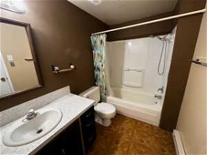 Full bathroom featuring shower / bath combination with curtain, toilet, parquet flooring, vanity, and baseboard heating