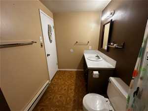 Bathroom featuring baseboard heating, toilet, and vanity