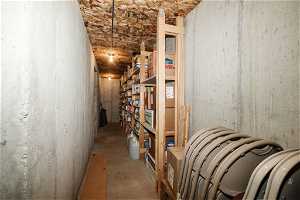 View of storage room with anchored/built shelving for storage.  Cool tempature for storage.