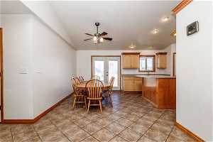 Tiled dining room with lofted ceiling, ceiling fan, and french doors to large backyard,