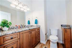 Bathroom featuring hardwood / wood-style floors, vanity, toilet, and a notable chandelier