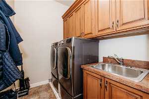 Laundry area featuring cabinets, light tile floors, sink, and separate washer and dryer