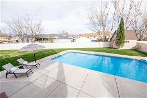 View of pool with a patio and a yard