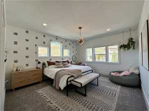 Carpeted bedroom with a notable chandelier and a textured ceiling