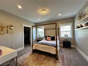 Carpeted bedroom with a textured ceiling, a closet, and a walk in closet
