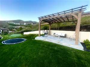 View of yard featuring a pergola, an outdoor living space, a patio, and a mountain view
