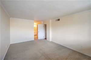 Empty room with ornamental molding and light colored carpet