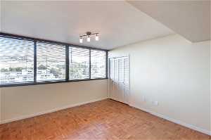 Unfurnished room with light parquet flooring and rail lighting