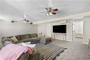 Living room with light carpet, ceiling fan, and a textured ceiling