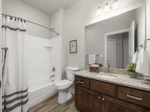 Full bathroom with hardwood / wood-style floors, vanity, toilet, and shower / bath combo