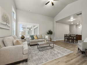 Living room with light hardwood / wood-style floors, vaulted ceiling, and ceiling fan