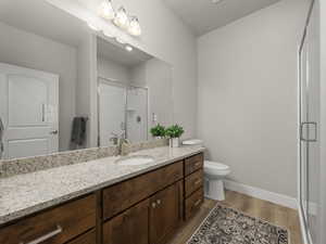 Bathroom featuring hardwood / wood-style floors, vanity, toilet, and an enclosed shower