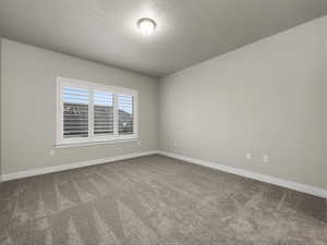 Carpeted spare room featuring a textured ceiling