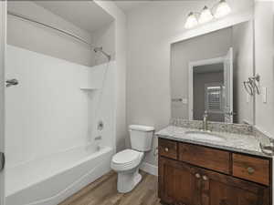 Full bathroom featuring hardwood / wood-style flooring, vanity, toilet, and washtub / shower combination