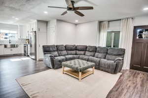 Living room featuring a textured ceiling, dark hardwood / wood-style flooring, ceiling fan, and sink