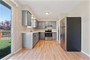 Kitchen featuring stainless steel appliances, light hardwood / wood-style flooring, and gray cabinets