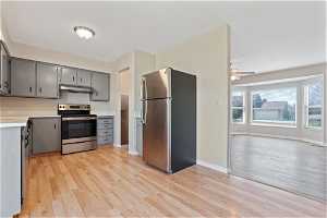 Kitchen with light hardwood / wood-style floors, stainless steel appliances, ceiling fan, and gray cabinets