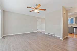 Empty room with light hardwood / wood-style flooring, ceiling fan, and sink