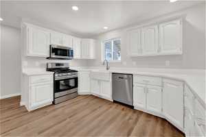 Kitchen featuring appliances with stainless steel finishes, light hardwood / wood-style floors, and white cabinetry